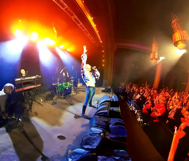 An image of Queen Mother playing on a stage in front of a crowd.