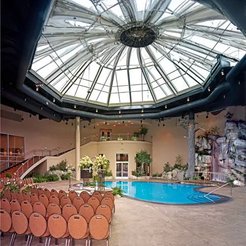 An image of the pool area set up for an event showcasing the chairs facing the pool area and the stairs coming down from the second story.