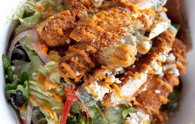 An image of crispy chicken on a bed of salad.